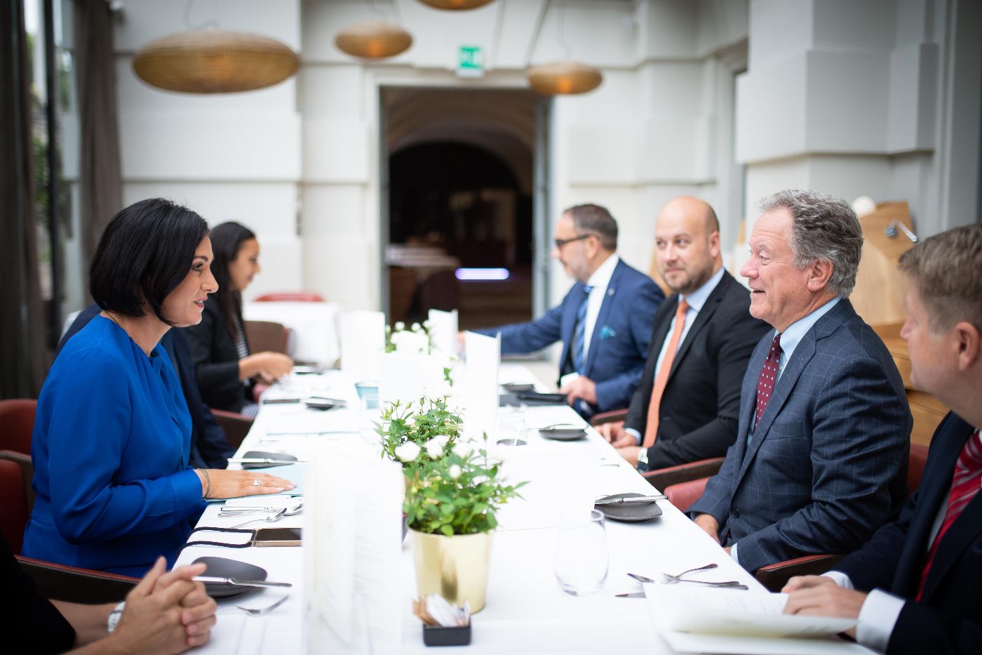 Bundesministerin Köstinger, David Beasly, Direktor des Welternährungsprogramms, und weitere Personen sitzen gemeinsam am Tisch und sprechen miteinander