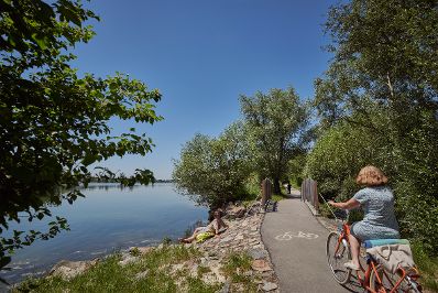 Radfahrerin entlang eines Seeufers